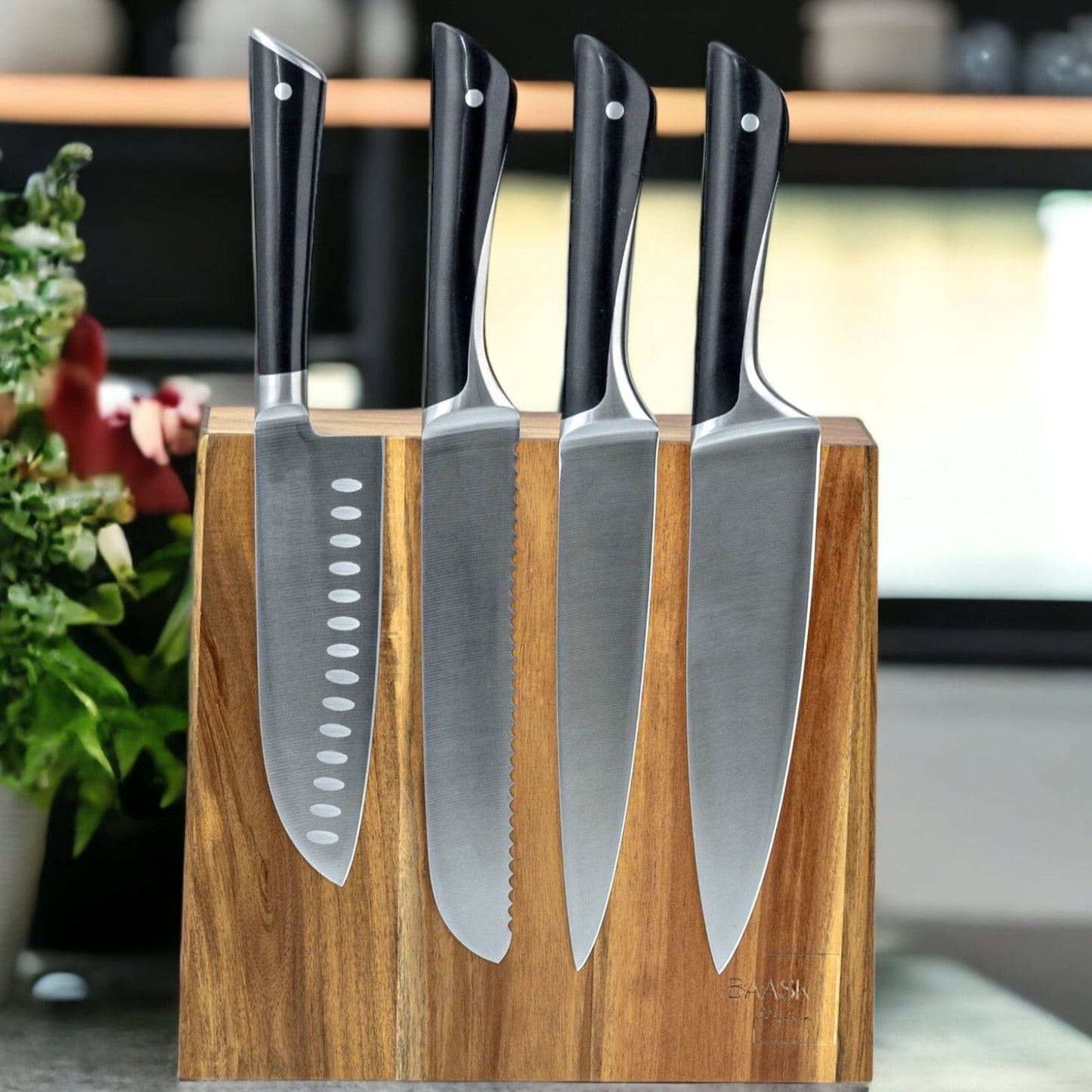 Magnetic knife block with knives on grey granite kitchen counter top and pot of green herbs