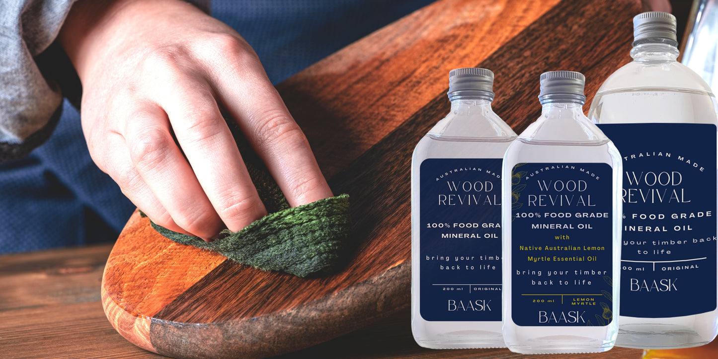 chopping board oil original and lemon myrtle varieties on display. Hand with green cloth being used to polish wooden cutting board